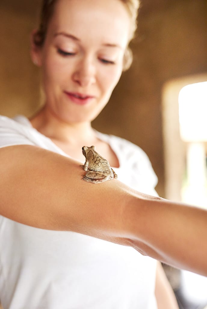 She loves all animals the same. Shot of a tiny frog sitting on a womans arm.