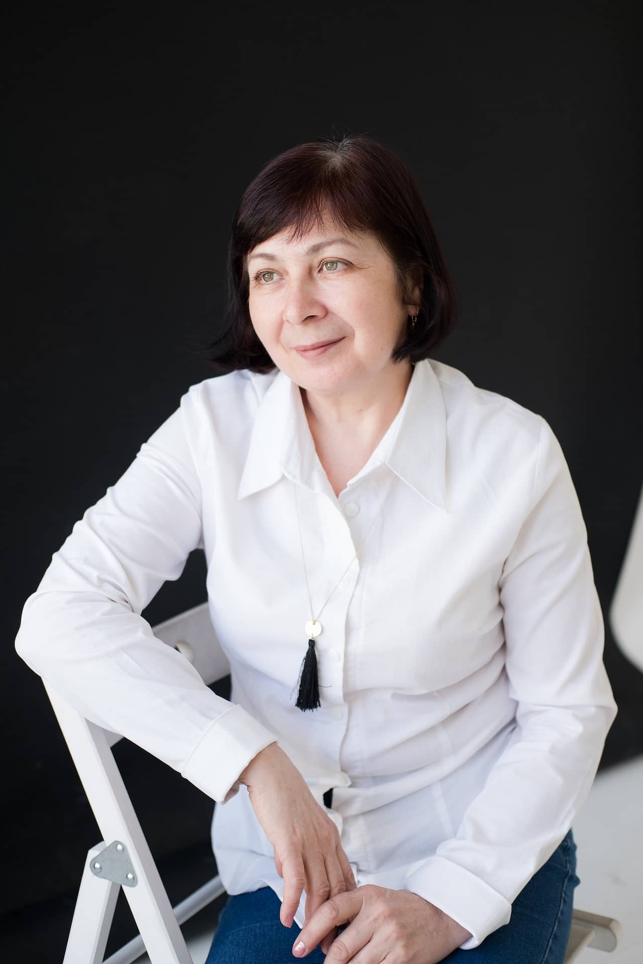 portrait of a woman 50 years old, with a short haircut, in a white shirt and jeans