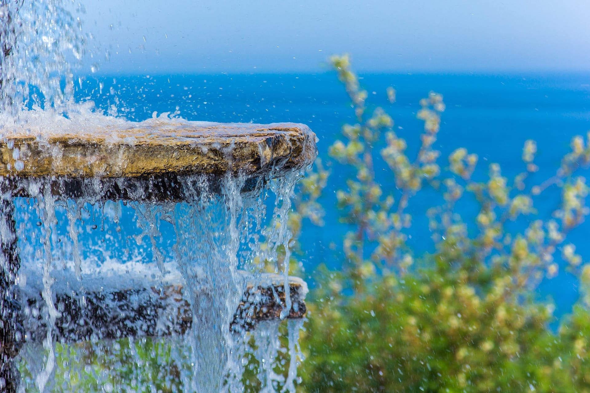 The gush of water of a fountain against the blue sea