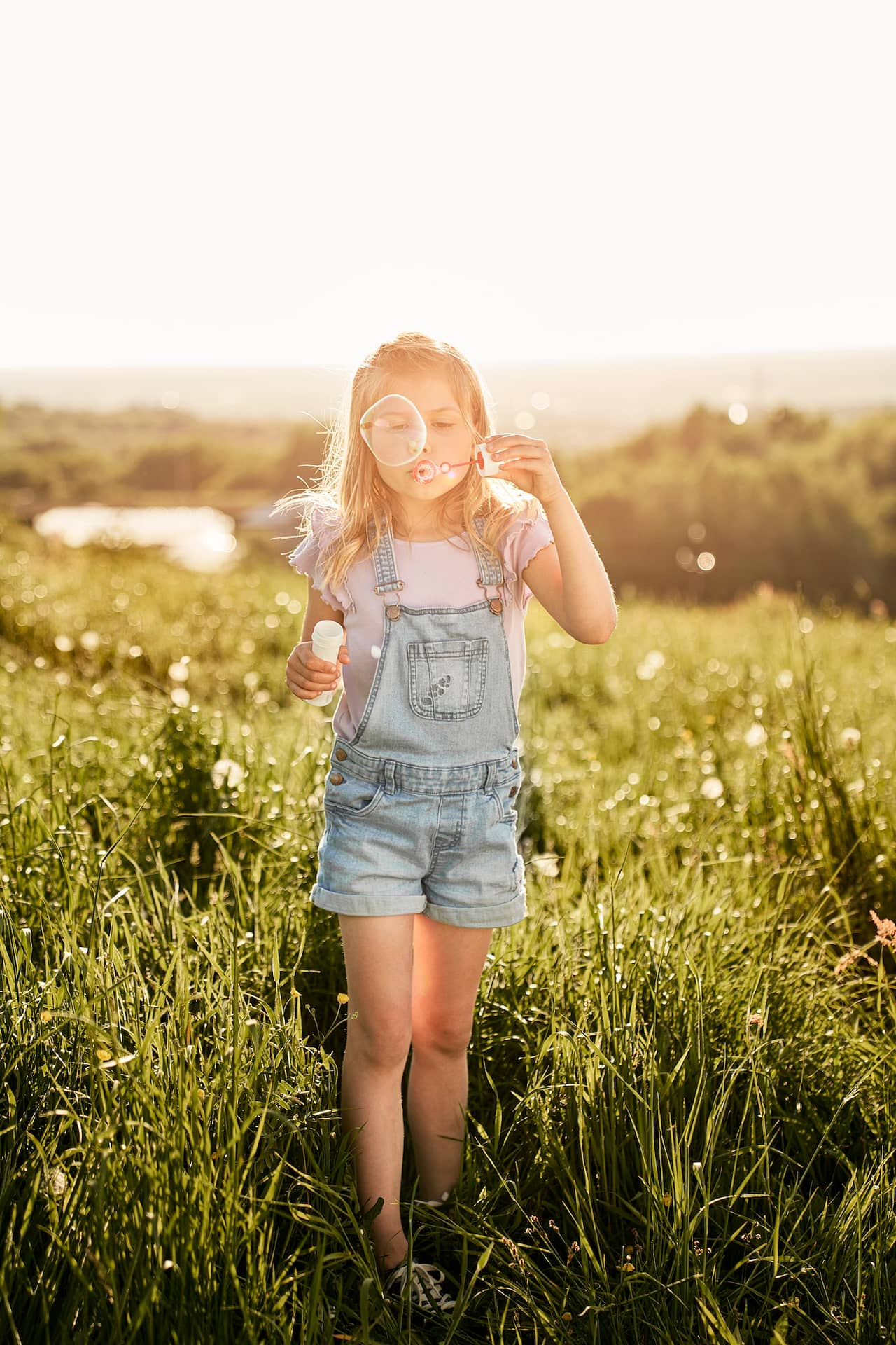 Caucasian girl playing with bubbles on the meadow